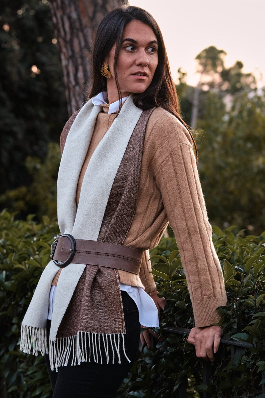 Modelo mujer en un jardín verde con una bufanda de baby alpaca de color chocolate y blanco