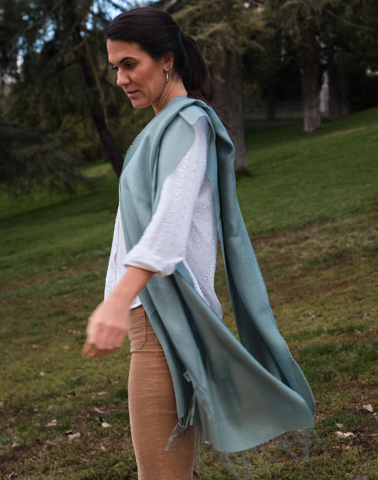 Modelo mujer vistiendo un chal de baby alpaca y seda de color frost green en un entorno campestre