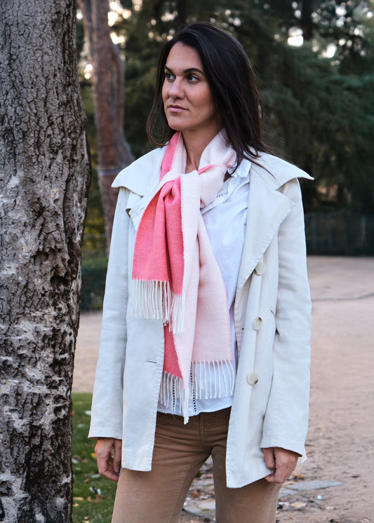 Mujer con bufanda de lana de baby alpaca de color coral y blanco en un parque