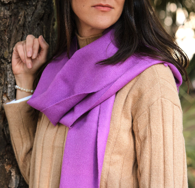 Modelo femenina morena en la naturaleza con una bufanda de lana de baby alpaca color dahlia vista de cerca