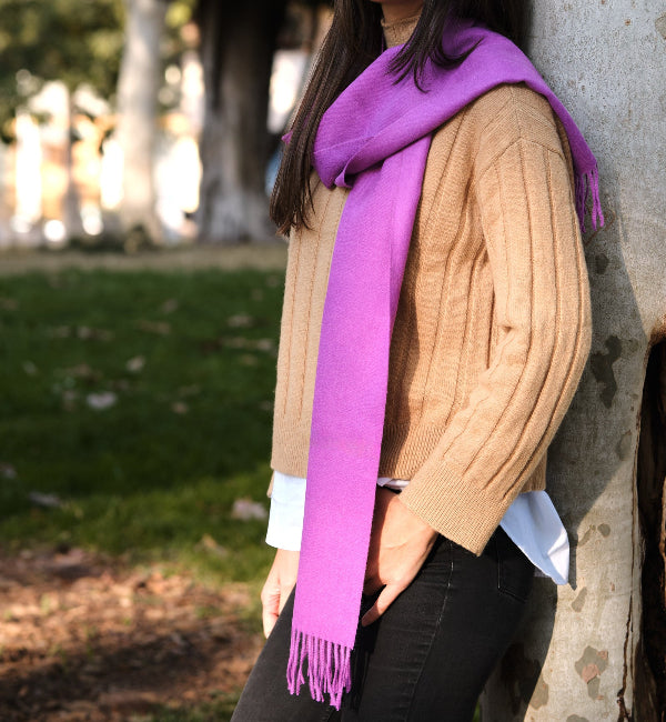 Modelo femenina morena en la naturaleza con una bufanda de lana de baby alpaca color dahlia