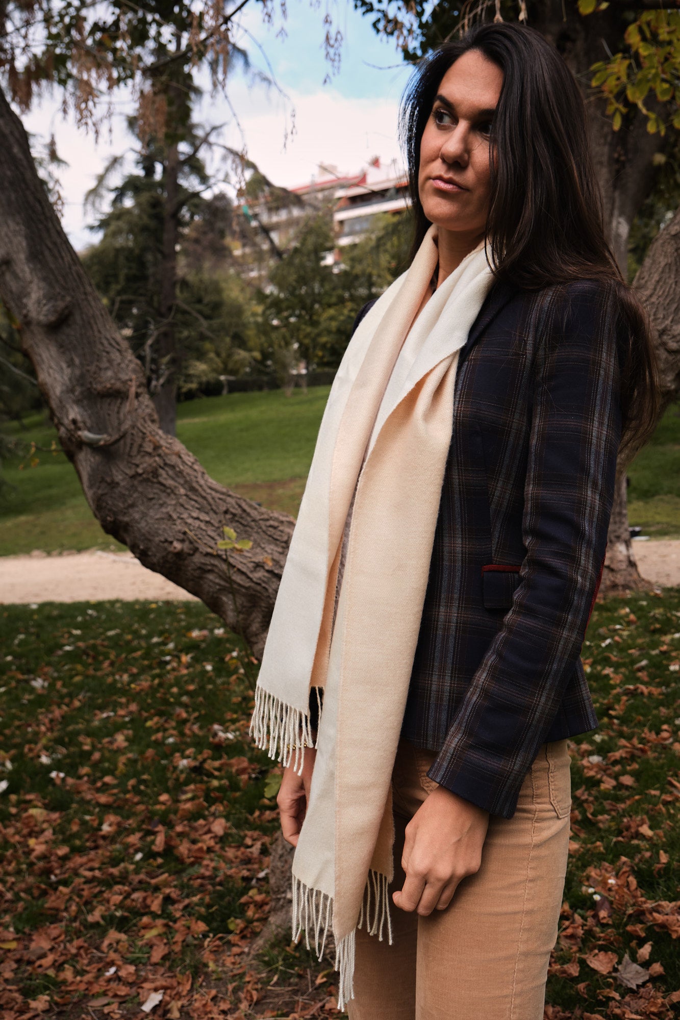 Modelo femenina en un entorno forestal con una bufanda de baby alpaca de color beige y blanco