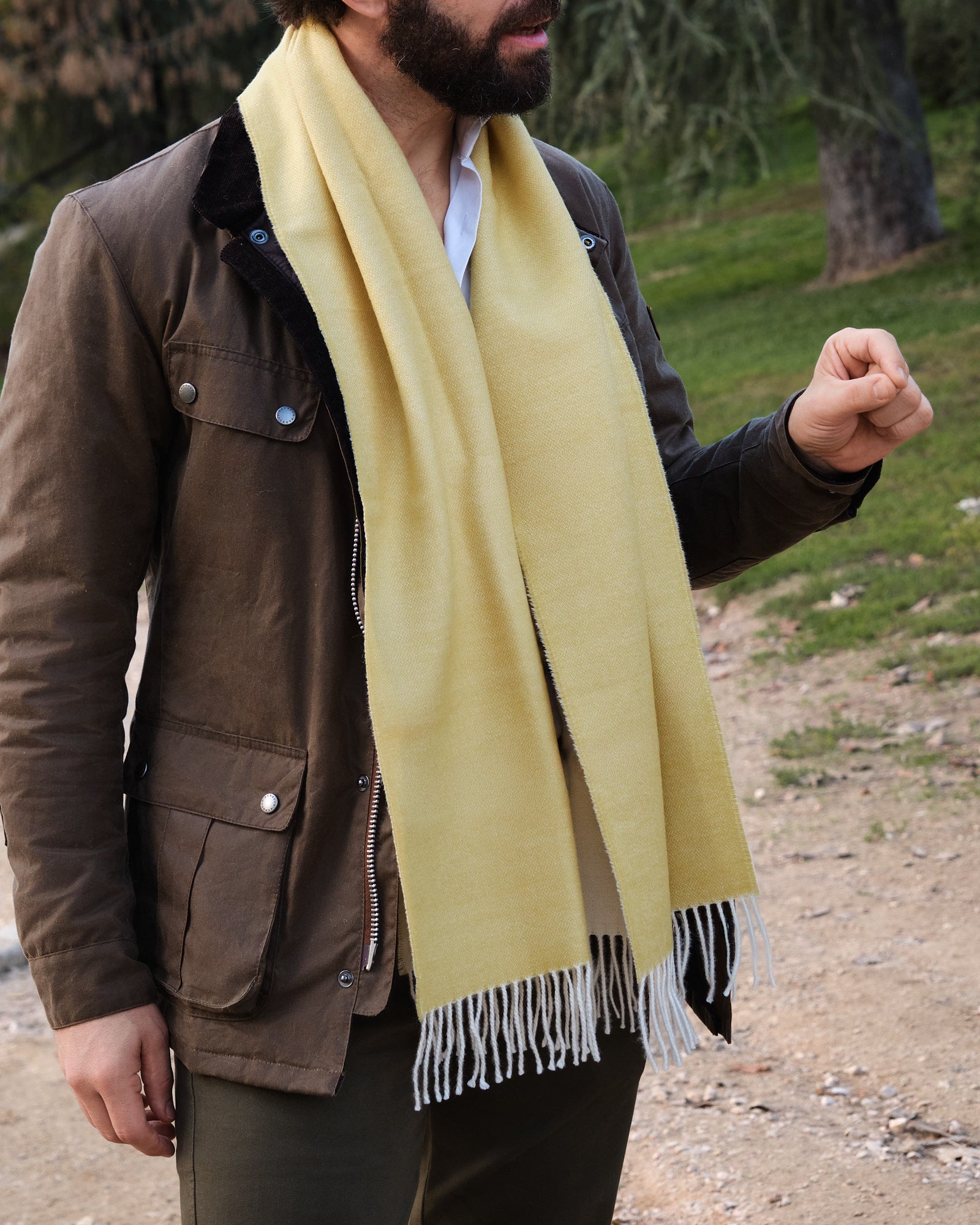 Hombre en el campo con una bufanda de baby alpaca de color amarillo y blanco