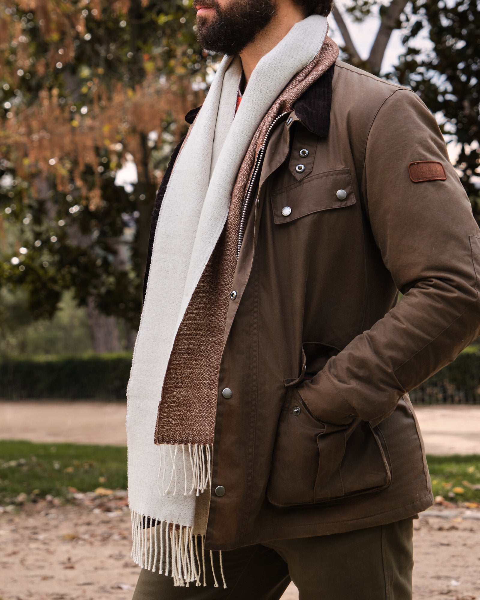 Hombre en un parque con una bufanda de baby alpaca de color marrón y blanco